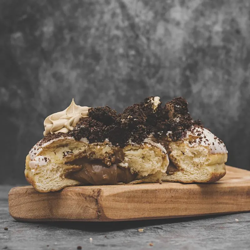 Donas cortadas sobre una tabla de madera, con relleno de chocolate y galleta triturada